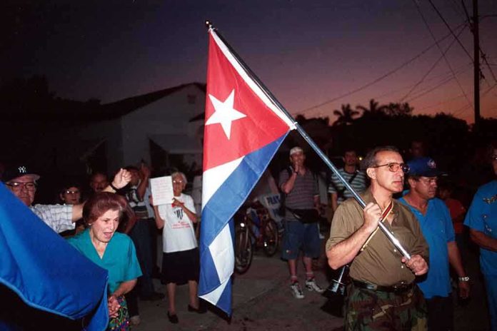 A group of people participating in a protest march holding a Cuban flag