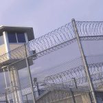 Iran Secretly Hangs Top Student – Torture Claims Guard tower behind barbed wire fence in a prison.