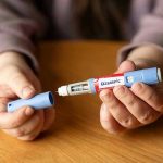 Weight Loss Miracle or Disaster? Hands holding an Ozempic injection pen.