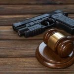 SCOTUS Shocks: Pot Users Keep Guns Gavel and gun on wooden table.