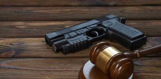 Gavel and gun on wooden table.