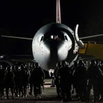 Soldiers boarding aircraft at night with staircase