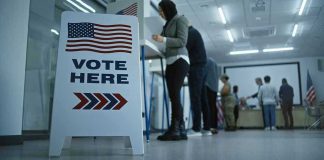 Perjury Bombshell Rattles Nebraska Senate Fight Sign reading Vote Here in a polling station.