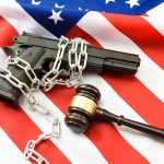 Court Says Suppressors Fit the 2A Text A handgun chained and placed on an American flag with a gavel nearby