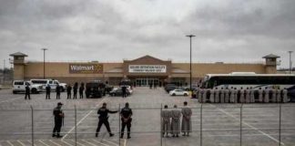 Law enforcement officers and detainees outside a secure detention facility at a Walmart location