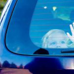 Child waving from the back window of car.
