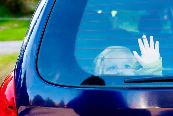 1050422462 Child waving from the back window of car.