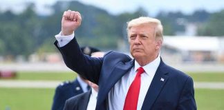 Trump ‘#1 Target’ On Iran’s ‘Kill List’ Man in suit raising fist near parked car.