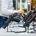 Guns By Mail? DOJ Pushes Wild Shift Display of handguns at a firearms exhibition with attendees interacting