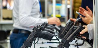 Guns By Mail? DOJ Pushes Wild Shift Display of handguns at a firearms exhibition with attendees interacting
