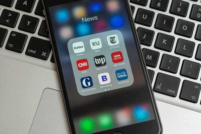 Smartphone displaying a folder of news apps on a laptop keyboard