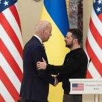 Two men shake hands at a podium with U.S. and Ukrainian flags