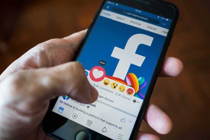 shutterstock_1050961571 Hand using smartphone with Facebook reactions on screen