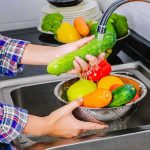 Parasite Explosion Stuns Michigan Hands washing cucumbers and bell peppers under a kitchen faucet