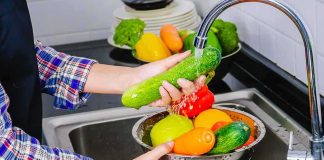 Parasite Explosion Stuns Michigan Hands washing cucumbers and bell peppers under a kitchen faucet
