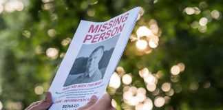 Hands holding a missing person flyer outdoors