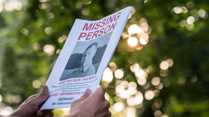 shutterstock_1420702217 Hands holding a missing person flyer outdoors