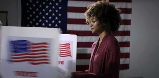 Voter at a polling booth with an American flag backdrop