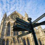 Archbishop Slams ‘Unholy’ Stage Stunt Gothic cathedral with ornate facade and directional signpost in foreground
