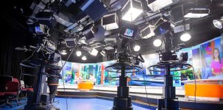 television studio with cameras on pedestals facing news desk