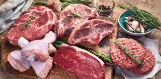 Assorted raw meat cuts with herbs on a wooden board