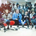 3 Leading News Outlets Say Sudden Banishment Is Unconstitutional Row of microphones at a press conference with audience and cameras behind