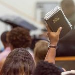 China Is Tightening Its Grip on Christians Hand holding a Bible in a crowded church service