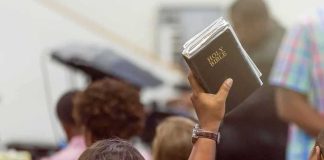 Hand holding a Bible in a crowded church service