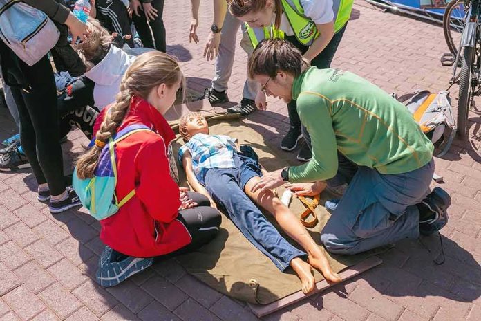 First aid trainees practice on a child manikin outdoors