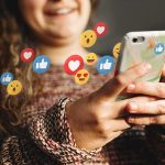 Meta HIT With $16.8 BILLION Settlement Person using smartphone with social media reaction icons floating around