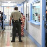 Governor Faces FURY After Illegal Stabs Woman Corrections officers escort an inmate in a jail hallway