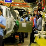 Canada Hits U.S. Back With Up to 50% Tariffs Teddy Williams on an automotive assembly line with workers fitting car doors