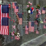 Ground Zero Mic Drop Stuns Crowd Memorial wall adorned with American flags and flowers