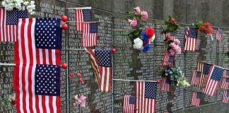 Ground Zero Mic Drop Stuns Crowd Memorial wall adorned with American flags and flowers