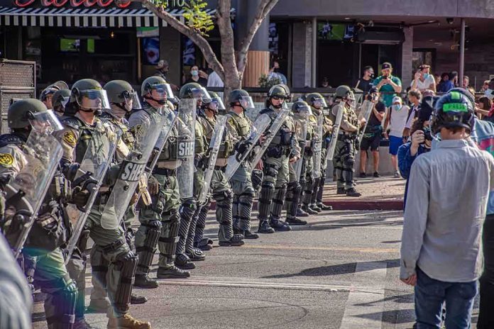 Riot police in helmets and shields form a line on a city street