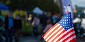 American flag on a small pole with a blurred outdoor crowd in the background