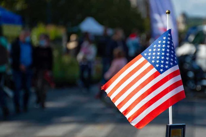 American flag on a small pole with a blurred outdoor crowd in the background