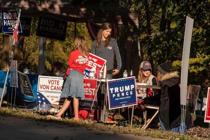 People at a political campaign table with signs and flyers outdoors