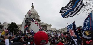 Crowd gathers outside the United States Capitol with numerous flags