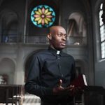 Priest speaking with a visitor inside a church