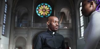Priest speaking with a visitor inside a church