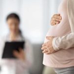 Surrogate Sued After Refusing to Abort Baby Pregnant woman holding belly during medical visit