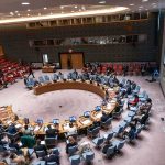 Existential AI Alarm Rocks UN Council Delegates seated around a circular conference table in a large chamber