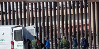 Mass Deportation Plan Hits a Massive Obstacle Border agents escort a group near a tall fence and a patrol van