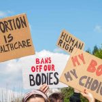 Graphic ‘Abortion’ TV Campaign Puts Trump on the SPOT Protesters hold cardboard signs at a rally outdoors