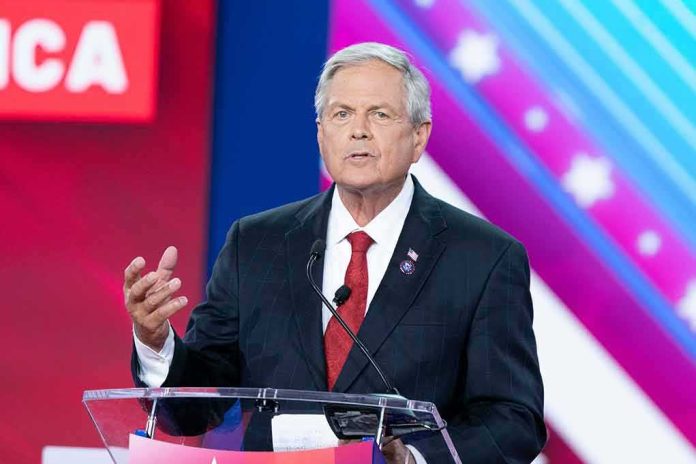 shutterstock_2186937109 Man in suit speaking at a podium on a colorful stage