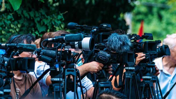 shutterstock_2210577723 TV news cameras crowding together at an outdoor event