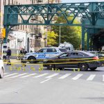 Police cars block a city intersection with yellow crime scene tape