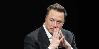 Elon Musk Joins Pentagon’s 120-Day Warfare Mission Elon Musk seated in a dark setting with hands steepled near his face