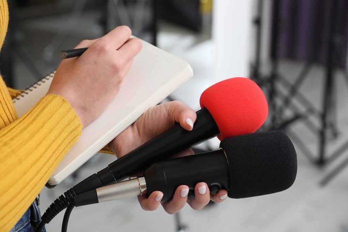 shutterstock_2431198207-2 Journalist holding two microphones while writing in a notebook